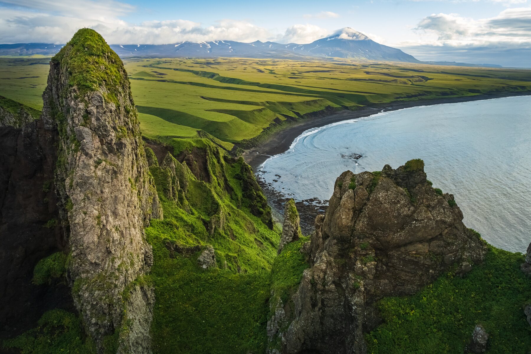 Green sea cliffs, black sand beach, and the Umnak coastline
